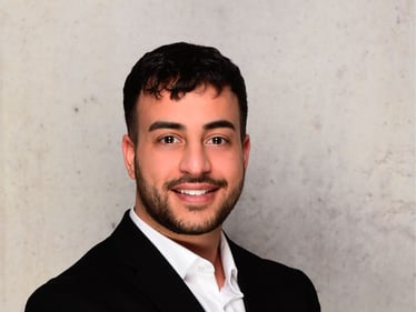 Das Foto zeigt den Agenturleiter Okan Kizilay in einem schwarzen Anzug lächelnd