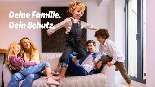 Fünfköpfige Familie sitzt lachend auf der Couch - Welche Versicherungen sind für Familien in Mainz wirklich wichtig?