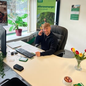 Auf dem Foto sehen Sie Jannik Thomassen am Schreibtisch sitzend mit dem Telefon am rechten Ohr.