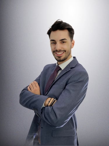 Das Foto zeigt den Agenturleiter Leandros Mpasouris mit einem freundlichen Lächeln. Der Agenturleiter trägt einen blauen Anzug mit Krawatte.