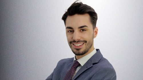 Das Foto zeigt den Agenturleiter Leandros Mpasouris mit einem freundlichen Lächeln. Der Agenturleiter trägt einen blauen Anzug mit Krawatte.