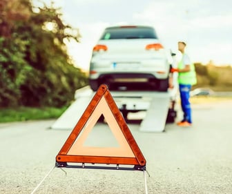 Auto auf einem Abschleppwagen und vorne im Bild ein Warnschild