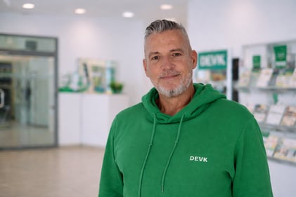 Foto des Agenturleiters Jens Lenz mit grünem DEVK-Hoodie, lächelnd