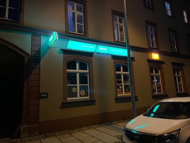Außenansicht der DEVK-Geschäftsstelle Mario Steinert in der Schloßstr. 22 in Chemnitz bei Nacht mit beleuchtetem grünem DEVK-Schriftzug