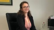 Das Foto zeigt die Agenturvertreterin Virginia Kremer lächelnd am Schreibtisch in der DEVK-Geschäftsstelle in Rommerskirchen