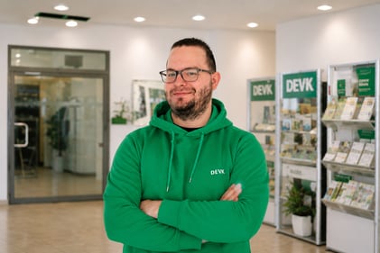 Foto von Florian Hannemann im grünen DEVK-Hoodie, freundlich lächelnd