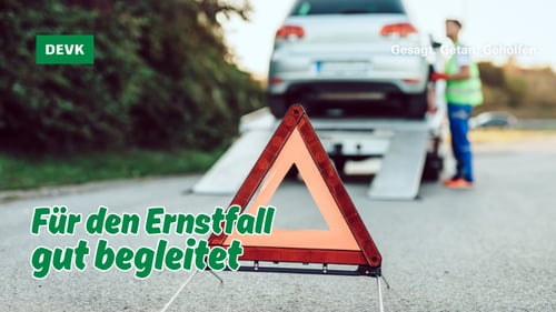 Abschleppdienst lädt ein liegen gebliebenes Auto auf, im Vordergrund steht ein Warndreieck mit dem Hinweis „Für den Ernstfall gut begleitet“