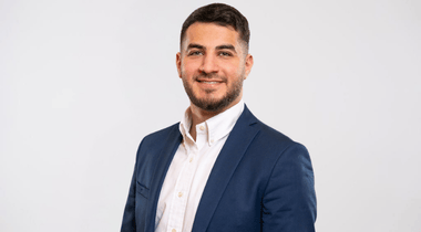 Das Foto zeigt den Mitarbeiter Mustafa Ramadan, lächelnd im Anzug.
