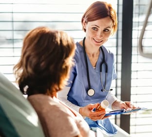 Bild mit einer Ärztin und Patientin am Krankenbett.
