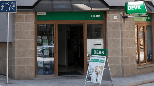 Das Bild zeigt den Eingang zum Büro der DEVK davor steht ein Werbeschild