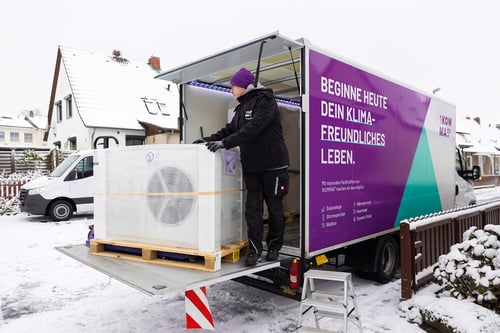 Monteure von 1KOMMA5° entladen eine Wärmepumpe von einem LKW und bereiten die Installation an einem Privathaus vor