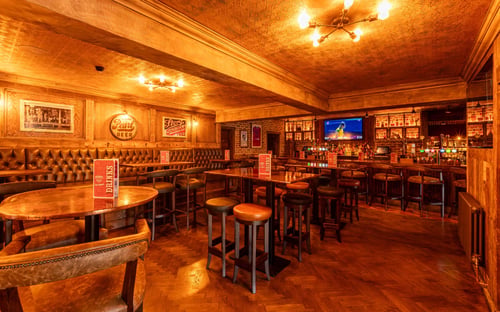 Bar area with high seats, tv screens, booth seating in Hickory's Adel
