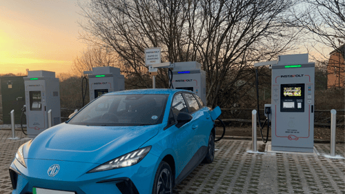 Blue electric vehicle charging at InstaVolt ultra rapid chargers on Peacock Lane in Bracknell at sunset