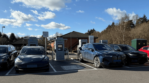 InstaVolt ultra rapid EV chargers at McDonald's A34 Burghclere, Newbury, with multiple electric vehicles charging under a clear blue sky.