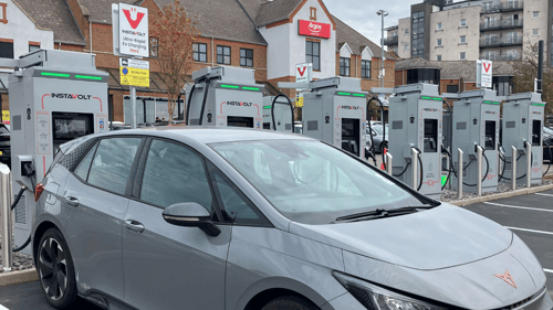 A row of InstaVolt ultra-rapid EV chargers in use at a retail car park near an Argos store.