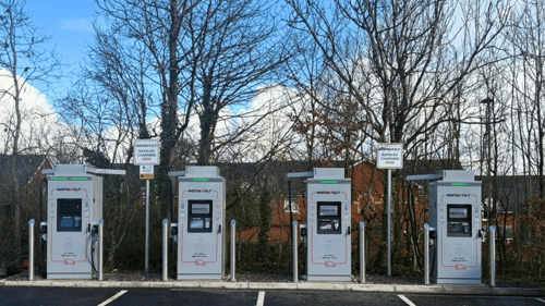 Row of InstaVolt ultra-rapid EV charging stations in McDonald's Exeter car park, ultra-rapid electric vehicle chargers with marked bays and surrounding trees.