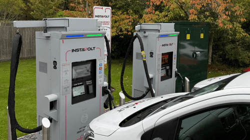 Two InstaVolt ultra-rapid EV chargers in use at Forest Lodge Hotel in Lyndhurst, with electric vehicles charging beside a grassy area and autumn trees.