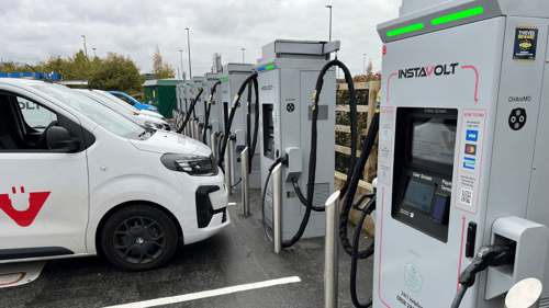 Row of InstaVolt ultra-rapid EV chargers in use at a public charging station with electric vans connected.