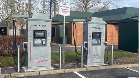 Two InstaVolt ultra rapid EV chargers installed at McDonald's Manchester Baguley, with a sign indicating 'Rapid EV Charging Here'. The chargers are positioned in a dedicated parking area with protective bollards.