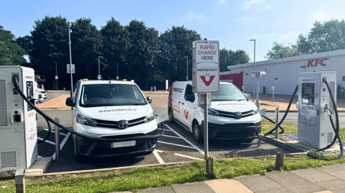 InstaVolt electric vehicle charging bays outside KFC Sheldon, featuring two white branded vans actively charging at ultra rapid units under clear blue skies.
