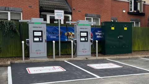 Two InstaVolt rapid chargers by a residential building with a signage board.