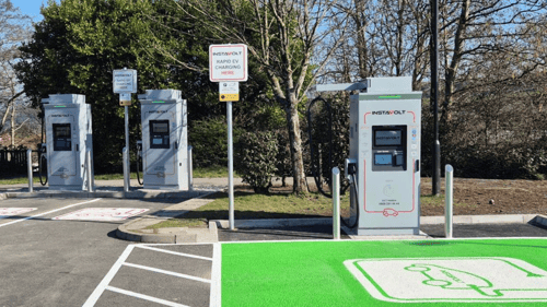 InstaVolt ultra rapid EV chargers at Cwmdu Retail Park, Swansea, featuring designated green parking bays and charging units under a clear sky.