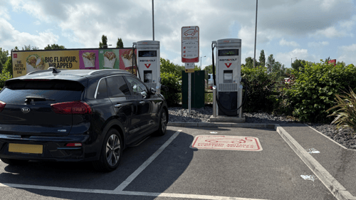 Kia electric vehicle charging at InstaVolt rapid chargers located at McDonald's Wincanton, with clear EV bay markings and advertising signage in the background.