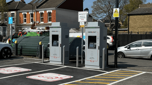 Two InstaVolt EV chargers installed in a residential area car park, with clearly marked EV-only bays and surrounding parked vehicles.