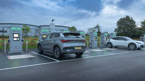 EVs parked and charging at InstaVolt bays with glowing green charger lights.