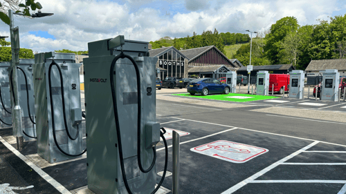 InstaVolt ultra rapid EV chargers at EH Booths, Windermere, with multiple charging bays and an electric vehicle charging in front of the Booths store.