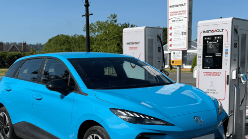 A blue electric vehicle charging at an InstaVolt ultra rapid charger at Chaldicott Farm in Semley, Shaftesbury, with clear signage and rural surroundings.