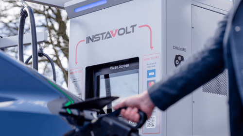 Driver using an InstaVolt ultra rapid EV charger at a public charging station.