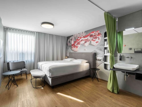 Discover the relaxing comfort of our thoughtfully designed rooms, where style meets functionality. Each room offers a plush double bed, smart TV, high-speed Wi-Fi, and seamless keyless entry. Night lamps with integrated phone holders and USB ports add an extra layer of convenience. All rooms are non-smoking, ensuring a fresh and comfortable environment. Look out over the enchanting Ljubljana skyline—you might just catch a glimpse of a dragon dancing through the clouds.