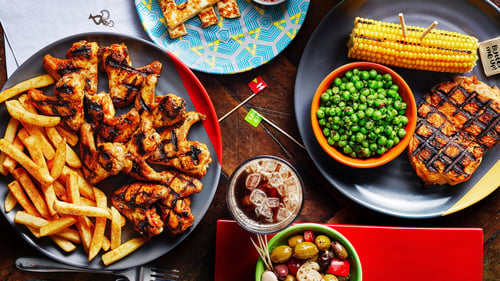 Nando's hot chicken wings with PERi Chips a bowl of Olives. A butterfly chicken with corn on the cob and Nando's macho peas